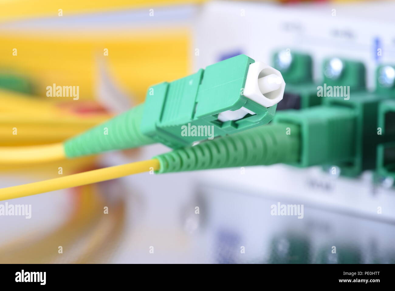 Passive Optical Network, Patch cord with Selective Focus and Network Equipment with Connected Cables in the Background Stock Photo