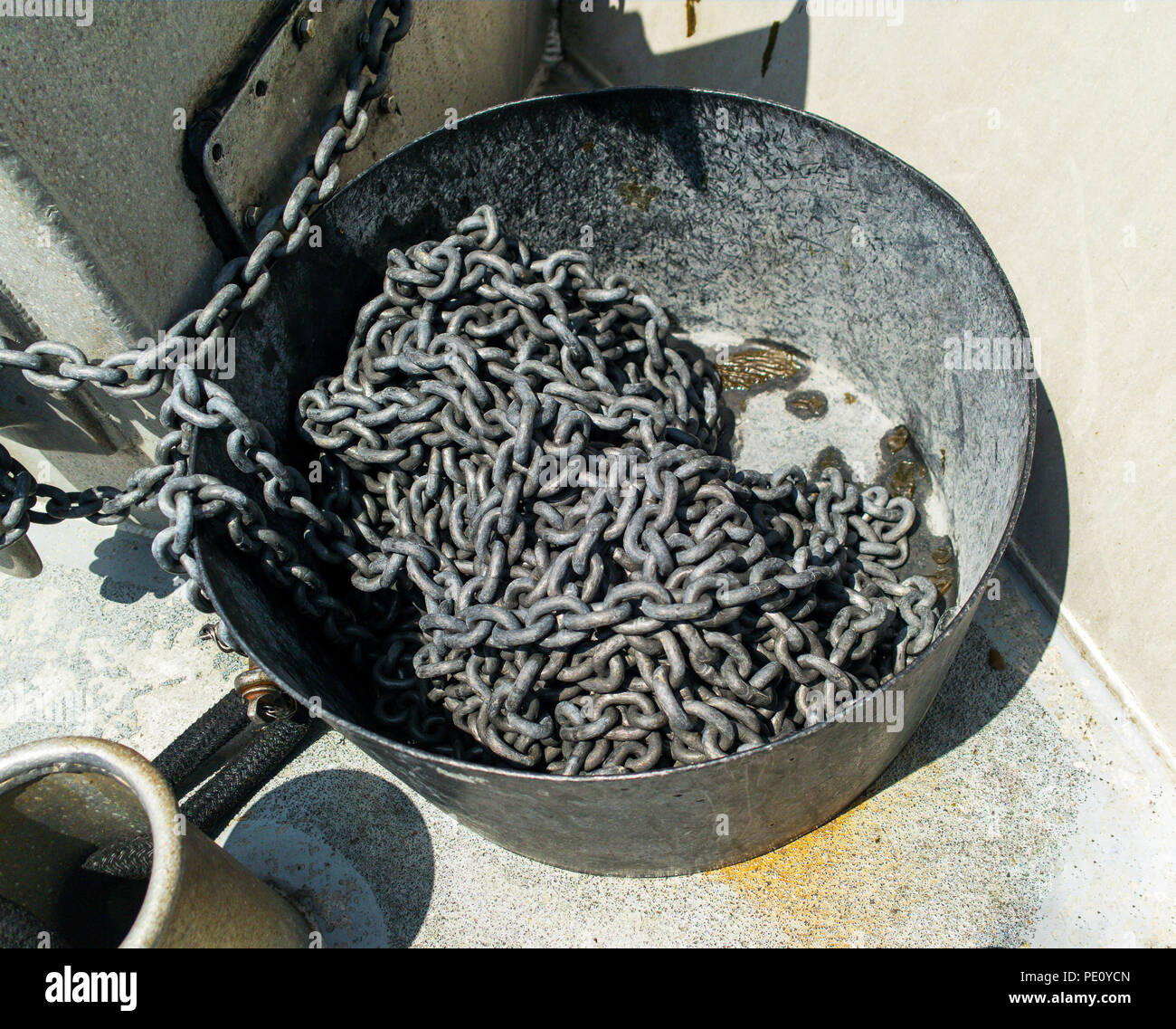 Fisherman boat with anchor chain insider large metal bin container. Silver anchor chain inside large metal container. Stock Photo