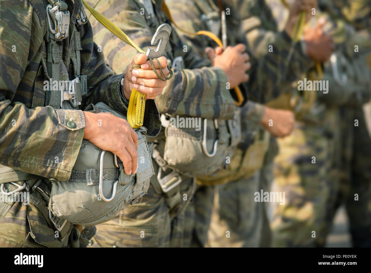 row of police paratrooper in camouflage uniform hold T-10 static line hook and parachute reserve in cinematic tone with copy space Stock Photo