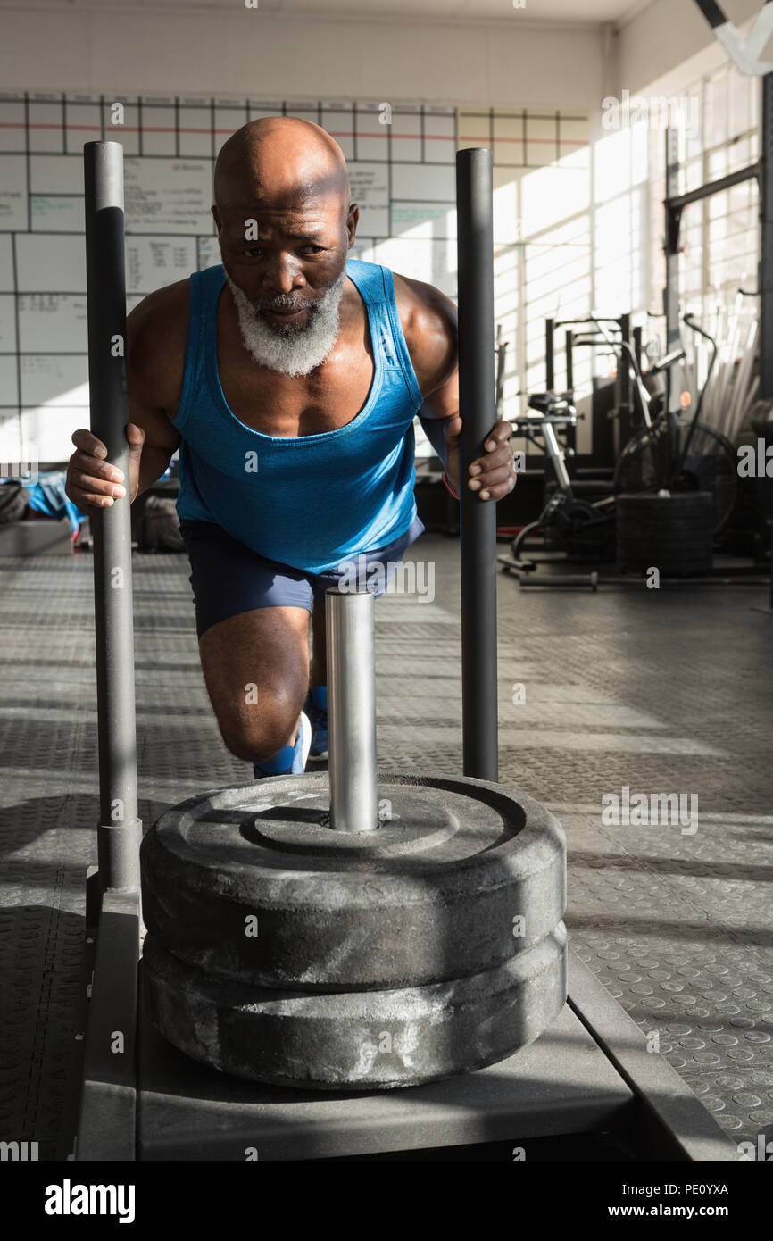 Senior man pushing weight sled in the fitness studio Stock Photo
