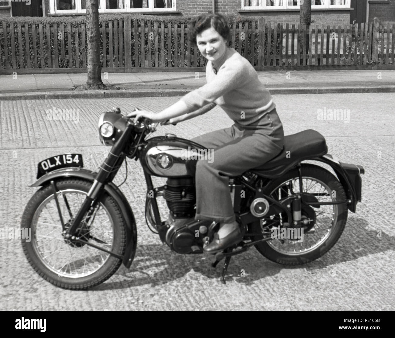 Attractive young lady sitting on 250cc BSA four-stroke motor cycle Stock Photo
