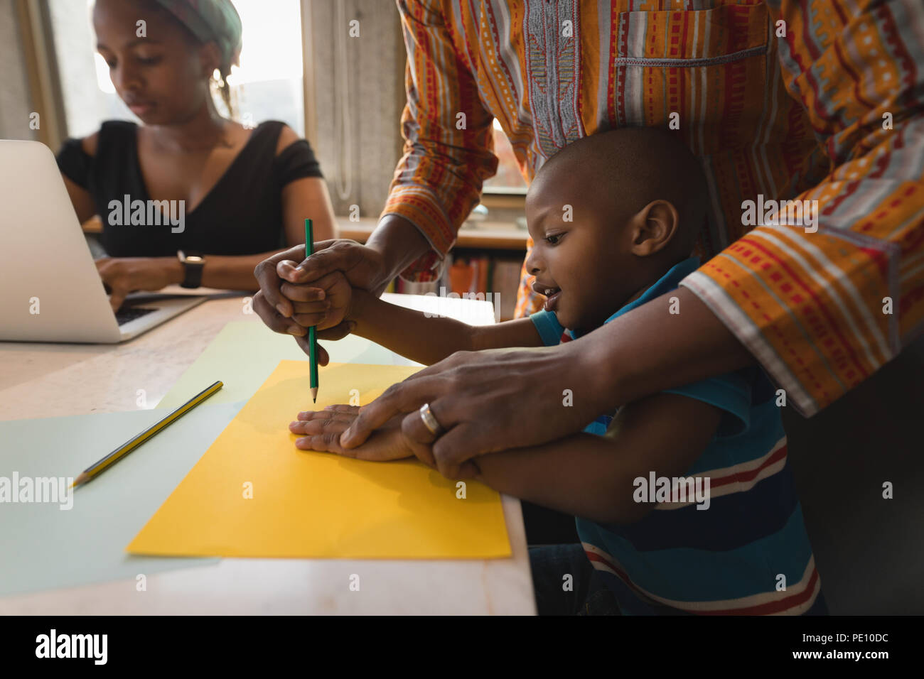 Father assisting her son to draw a sketch Stock Photo