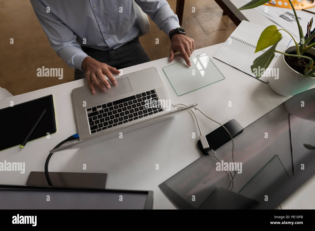 Businessman using glass digital tablet while working on laptop Stock Photo