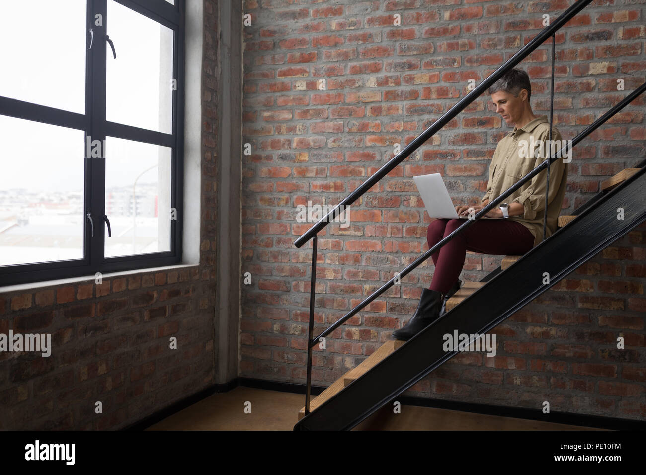 Businesswoman using laptop on stairs Stock Photo