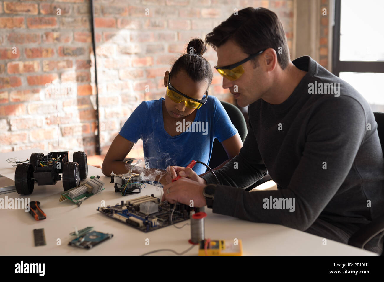 Father teaching her daughter about soldering iron Stock Photo