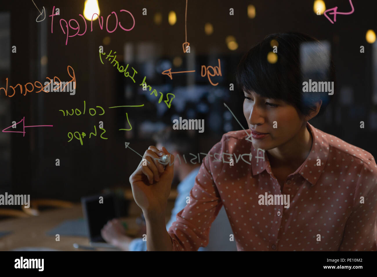 Female executive writing note on glass wall Stock Photo