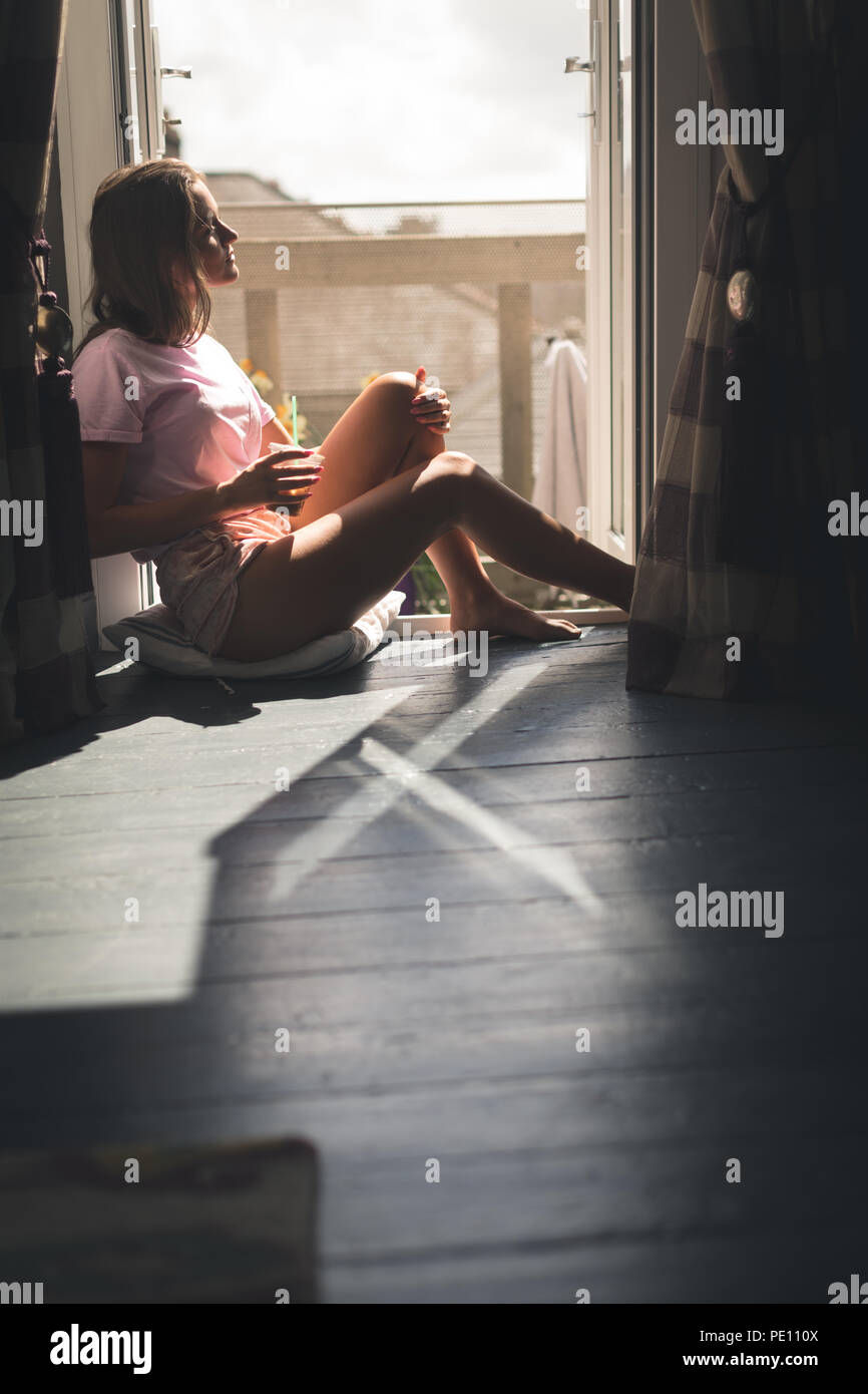 Woman sitting near window and having coffee Stock Photo