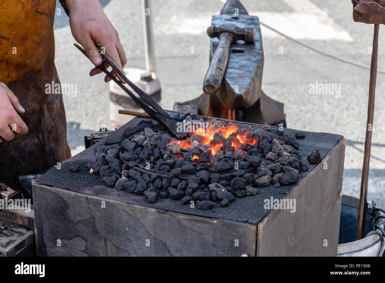 A blacksmith heating the metal stirrup hook he is making in a red hot ...
