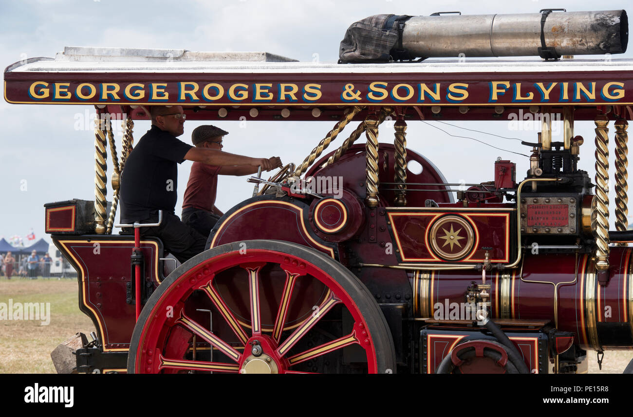 Father and son driving a showmans traction engine at a steam fair in England Stock Photo