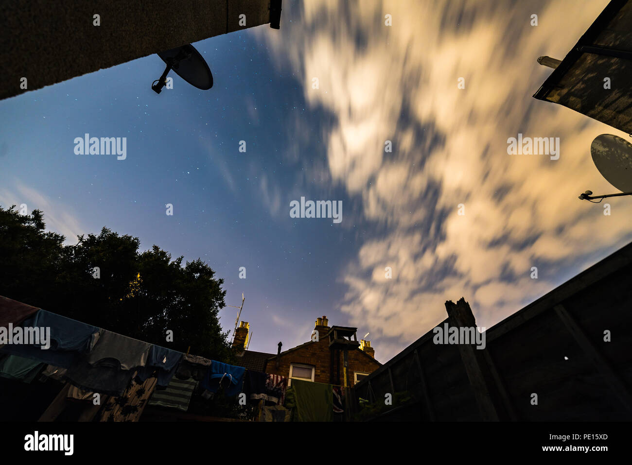 Night stars sky view from British backyard with laundry and satelite dishes around it. Stock Photo