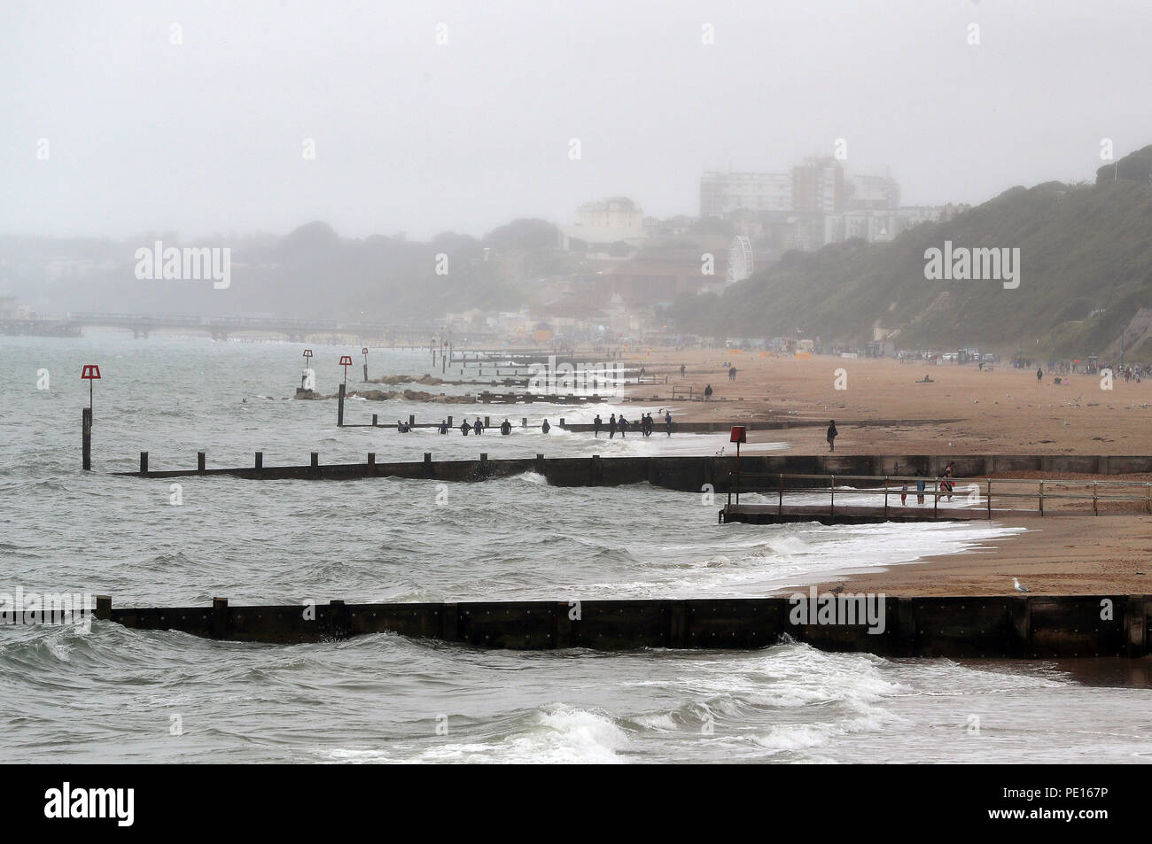 Swimmers take to the water as a small rain shower passes overhead on Boscombe beach in Dorset. Stock Photo