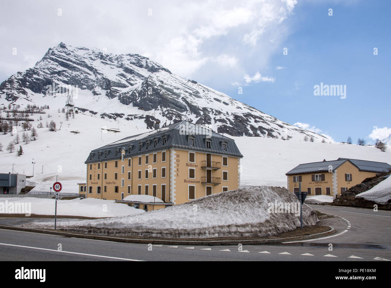 Bellevue Hotel and Restaurant at side of E62 Simplonstrasse road on north side of Simplon Pass in Switzerland with snow banks and building labelled Co Stock Photo