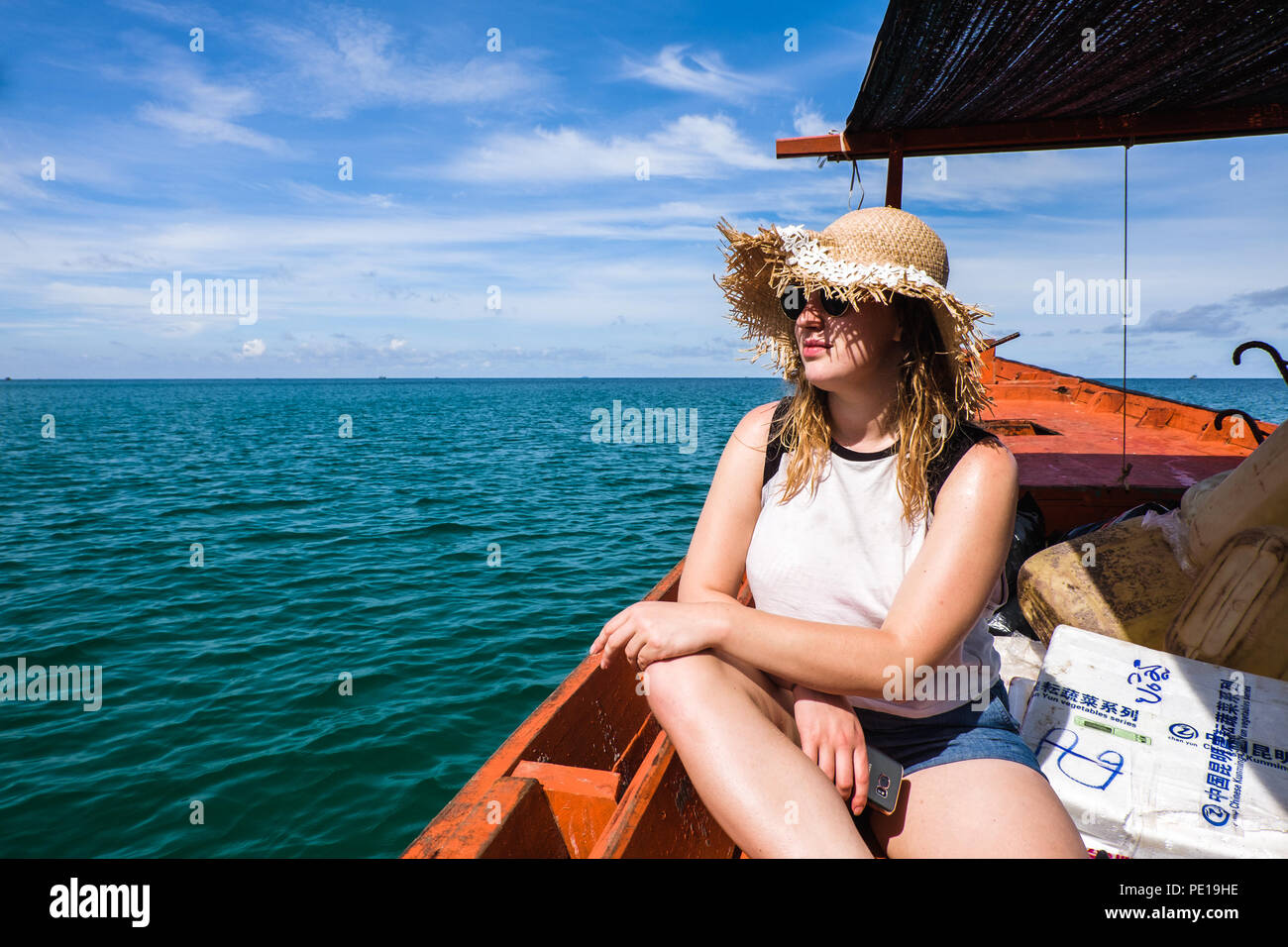 A woman on a budget-friendly wooden boat taking supplies and passengers between Koh Rong Samloem and Sihanoukville, Cambodia Stock Photo