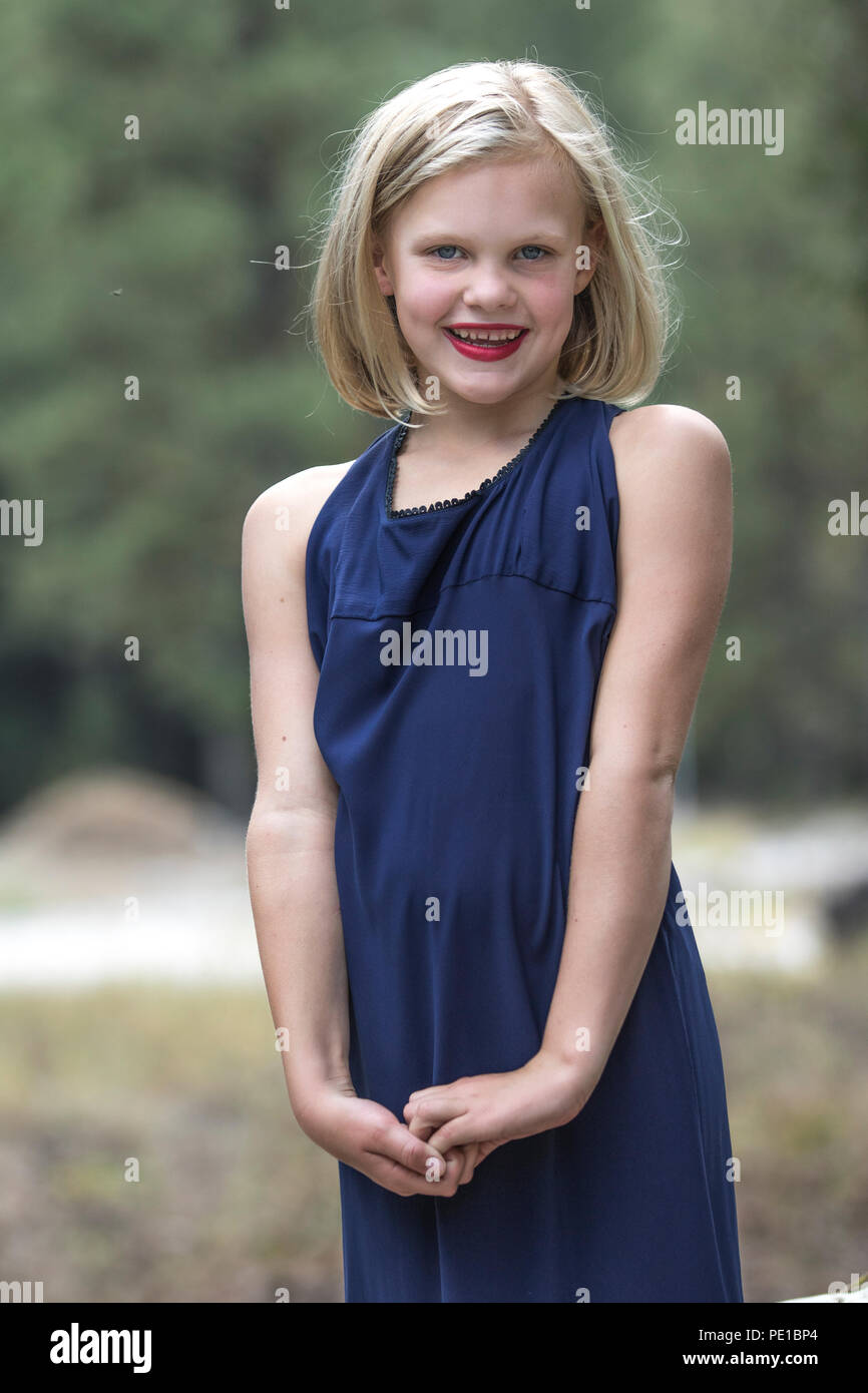 Pretty, young blonde female. preteen, Looking at camera smiling, laughing,  outside, 3/4 profile, blue dress, moody, model released Stock Photo - Alamy