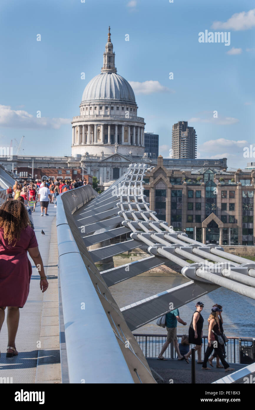 London landmark showing Millennium Bridge and St.Pauls cathedral on a bright sunny day with clear blue sky showing some tourists Stock Photo