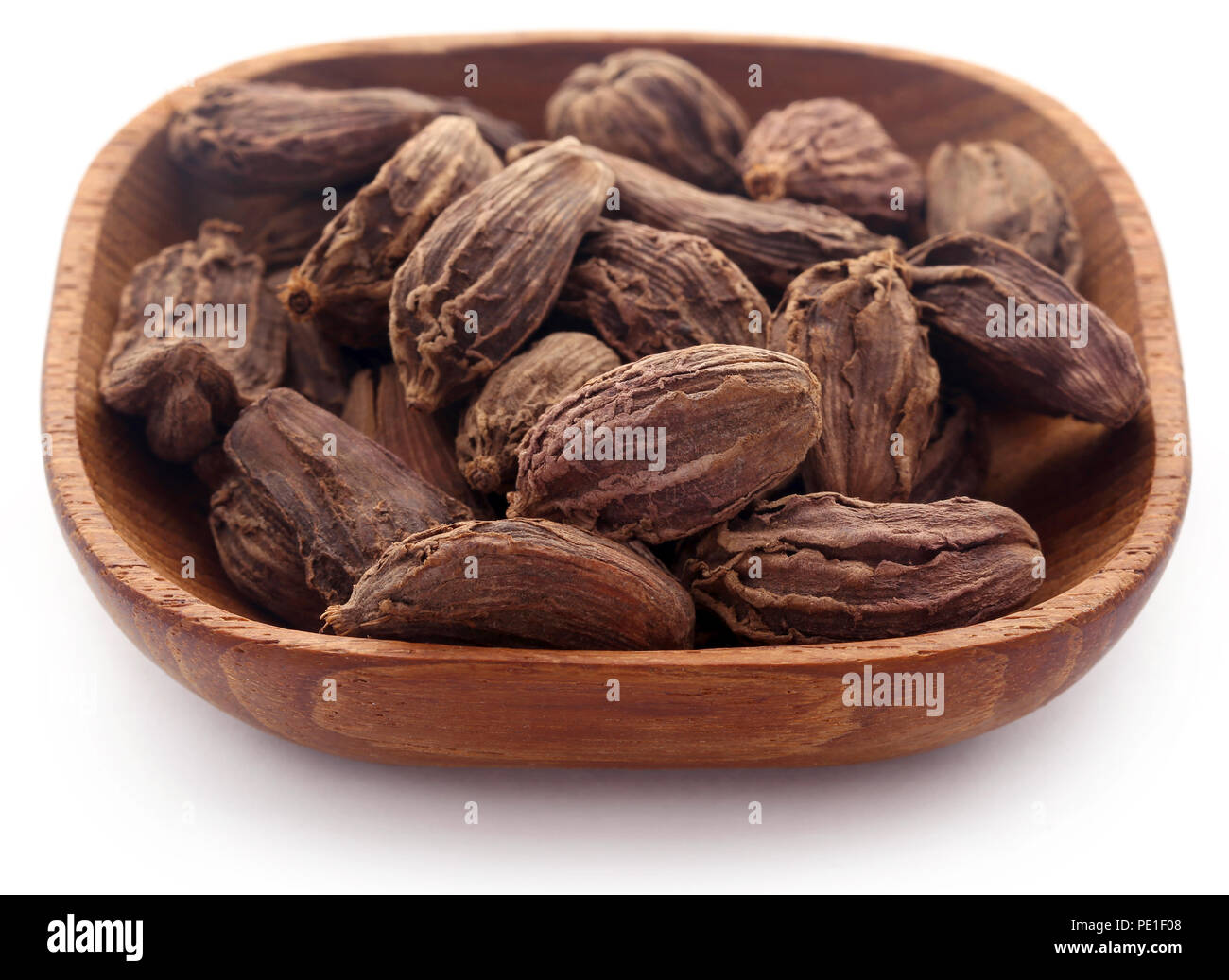 Black cardamom in bowl over white background Stock Photo