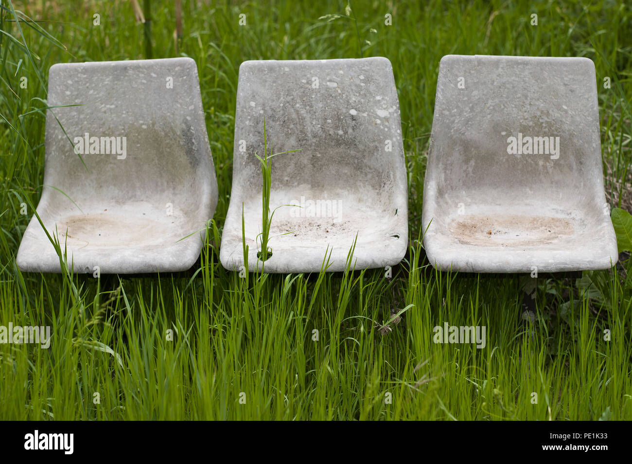 A trio of  old  abandoned moulded plastic chairs in a field in the commune of Varen, Tarn et Garonne, Occitanie, France  in springtime Stock Photo