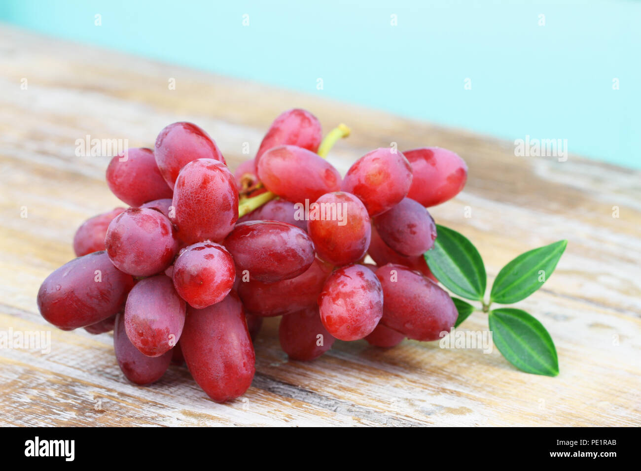 Red grapes in blue metal colander on rustic surface with copy space, closeup Stock Photo