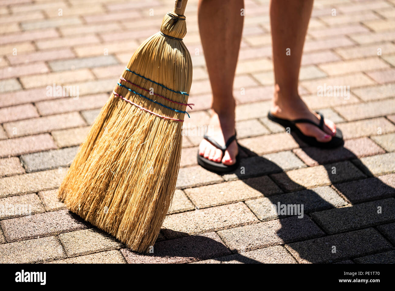 Young woman is sweeping the ground with a broom. Stock Photo