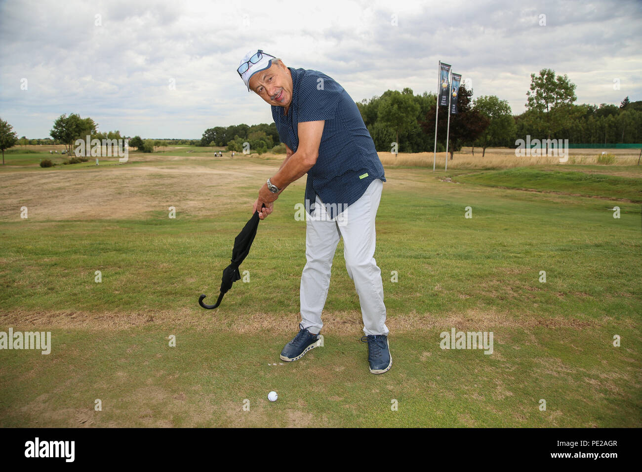 Machern, Germany. 11th Aug, 2018. Wolfgang Stumph humorously indicates a tee shot with an umbrella at the 11th GRK Golf Charity Masters at the Golf & Country Club Leipzig. Credit: Carl Seidel/dpa-Zentralbild/ZB/dpa/Alamy Live News Stock Photo