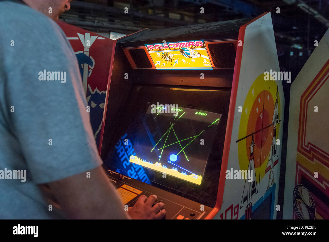 London, UK. 12 August 2018. A visitor plays Missile Command at retro games  festival PLAY Expo held in London for the first time at Printworks, Canada  Water. Game enthusiasts visited to rediscover