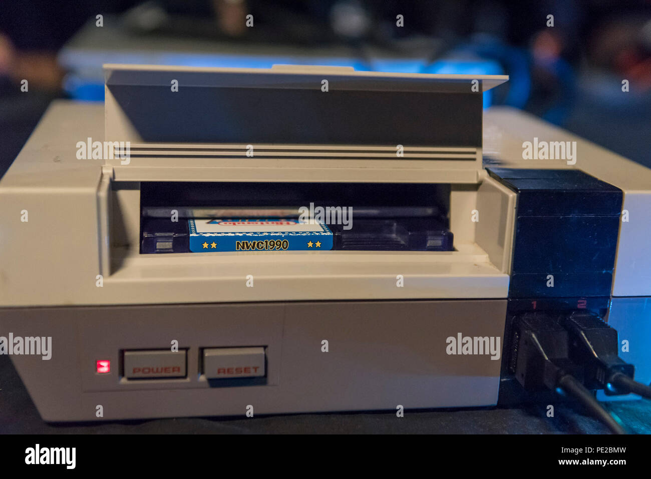 London, UK. 12 August 2018. A collectable games cartridge in a Nintendo  Entertainment System console at retro games festival PLAY Expo held in  London for the first time at Printworks, Canada Water.