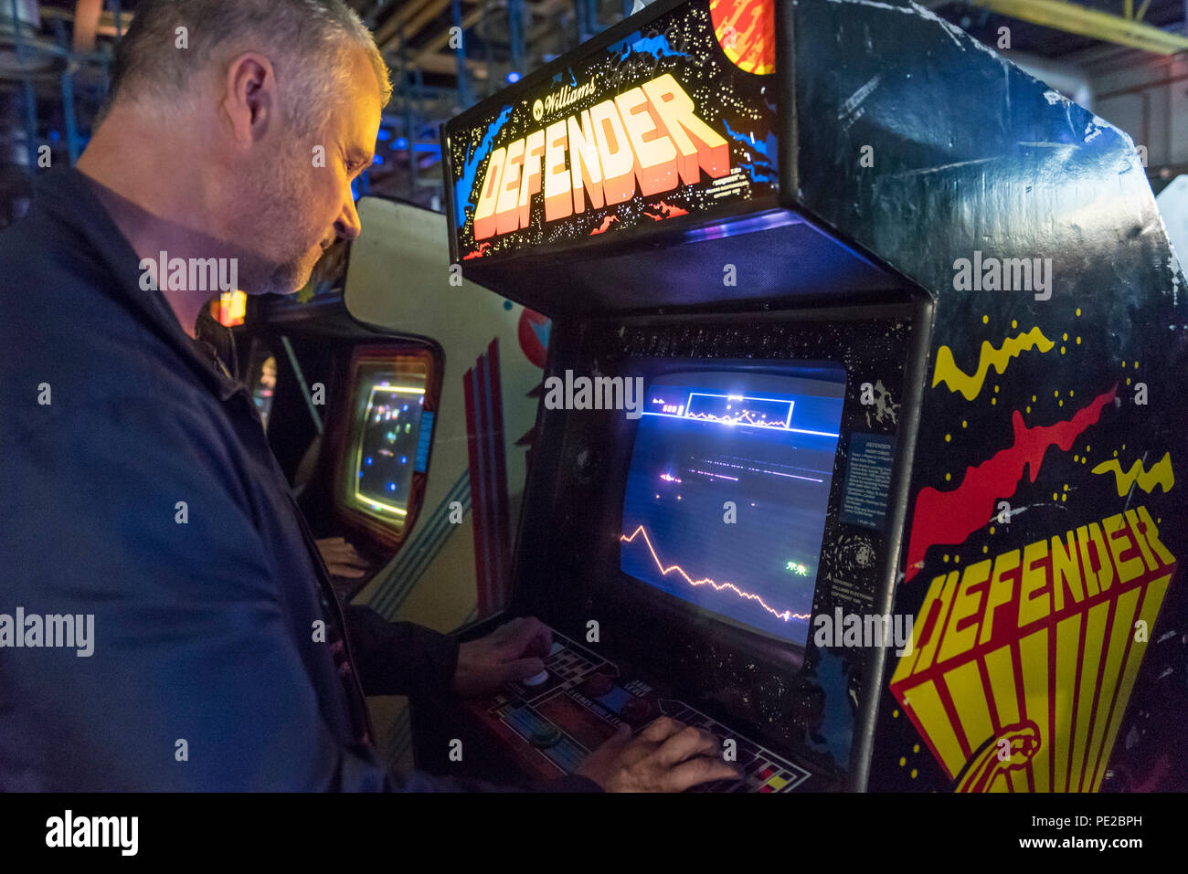 London, UK.  12 August 2018. A visitor plays Defender at retro games festival PLAY Expo held in London for the first time at Printworks, Canada Water. Game enthusiasts visited to rediscover the classics, from Donkey Kong, Pong, Super Mario Bros. and Space Invaders to vintage pinball machines, VR, indie games and a dedicated Minecraft zone. The show also included a sneak preview of new retro gaming streaming service, Antstream.  Credit: Stephen Chung / Alamy Live News Stock Photo