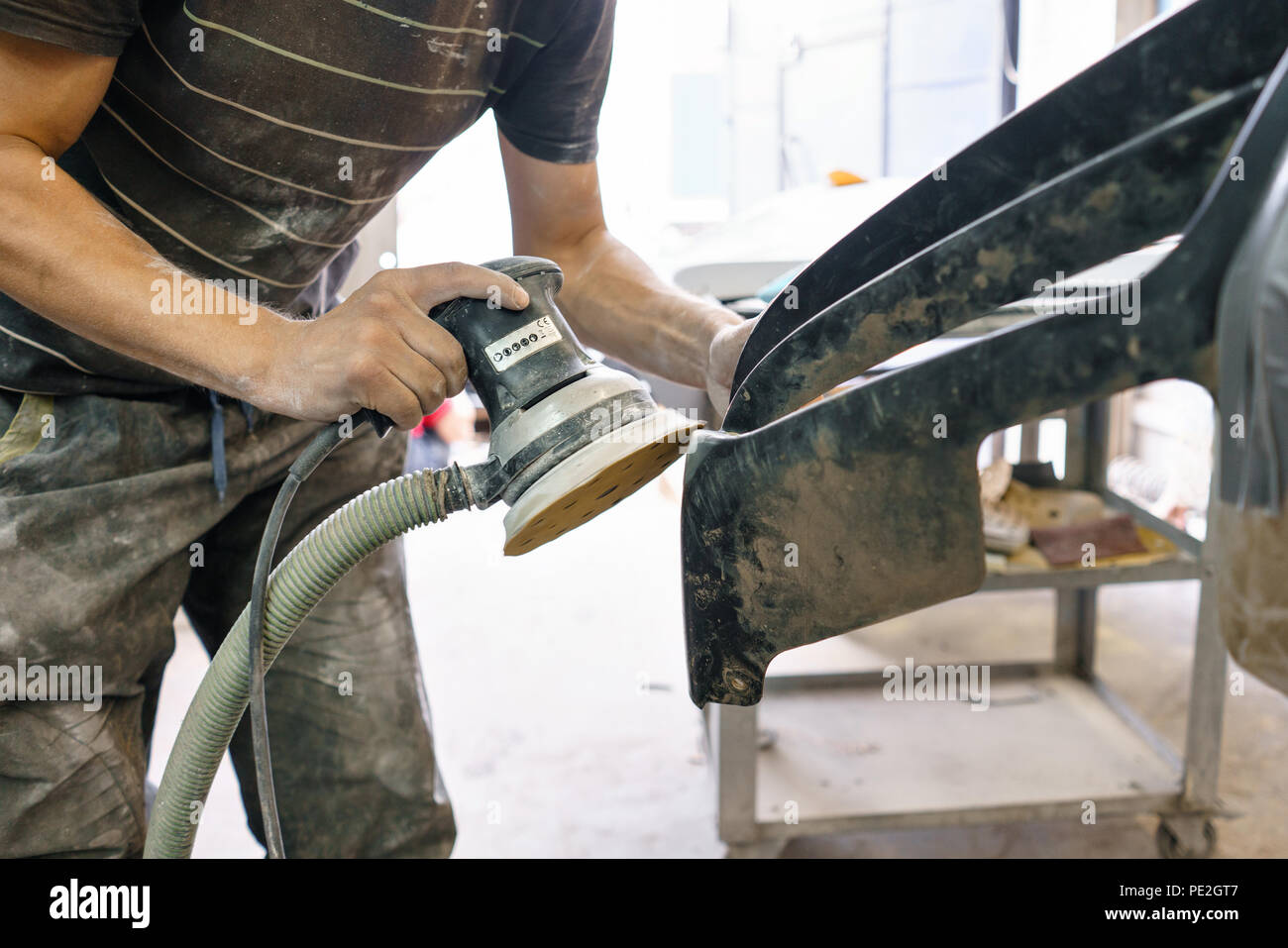 The mechanic works with a grinding machine. Garage painting car service