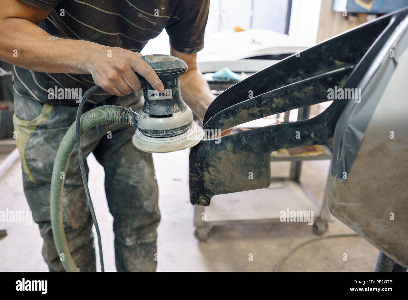 The mechanic works with a grinding machine. Garage painting car service