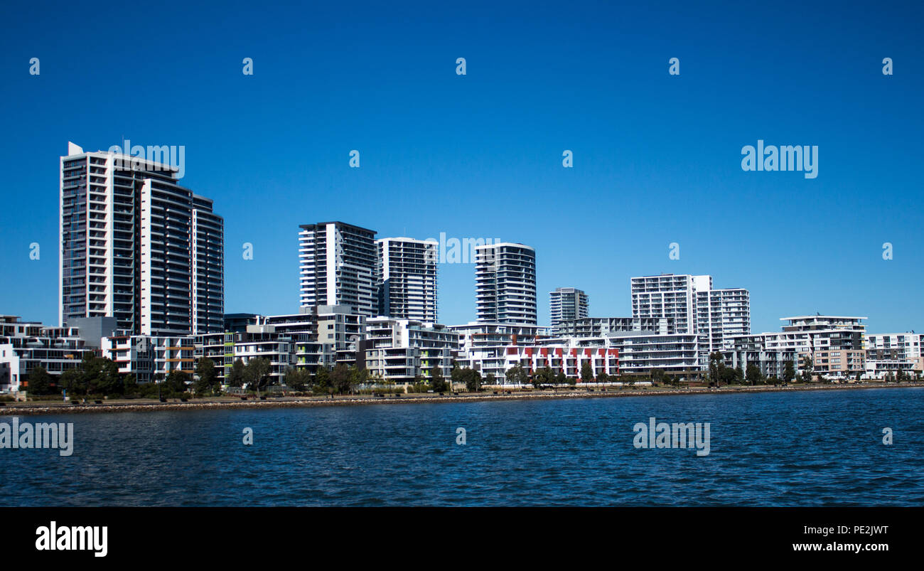 Australian waterside houses and condominiums with rock sea wall against blue sky Stock Photo