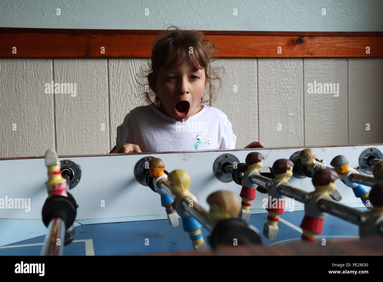Little girl playing fussball table Stock Photo - Alamy