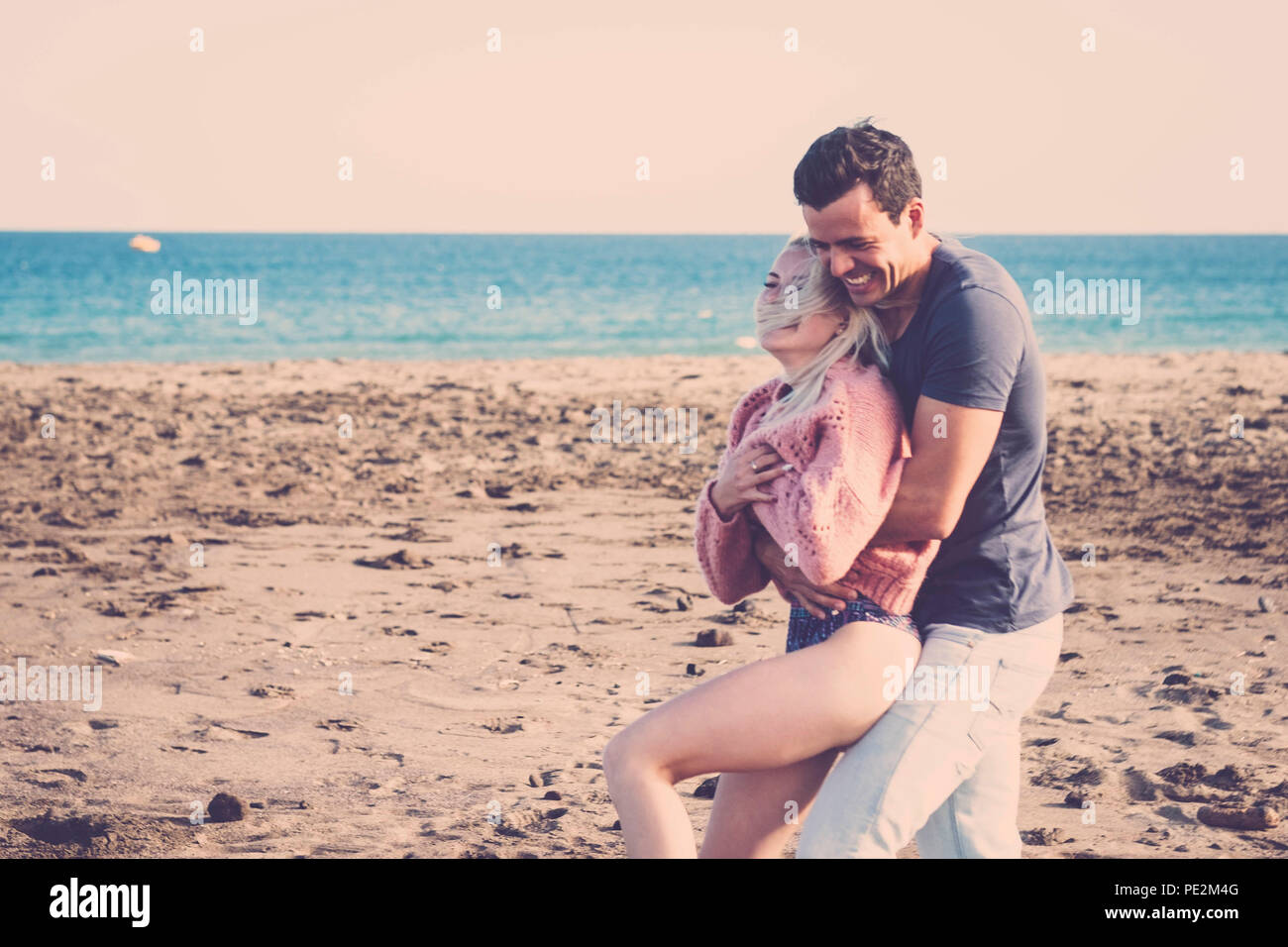 true and real happiness on these young beautiful people faces. nice blonde girl and cute black hair guy with big smile and laugh with ocean and beach  Stock Photo