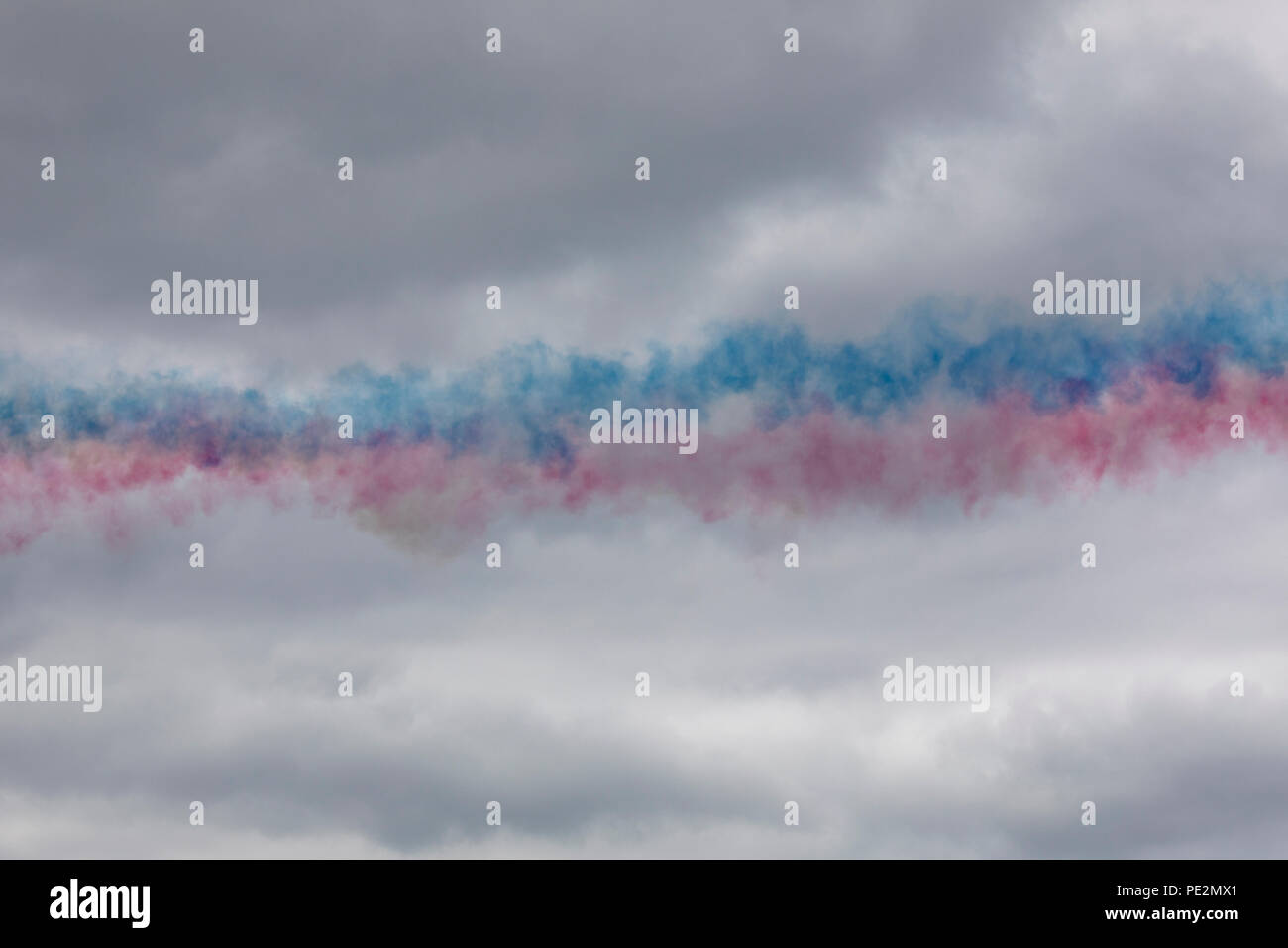 Coloured smoke lingering in the air after a Red Arrows flypast Stock Photo