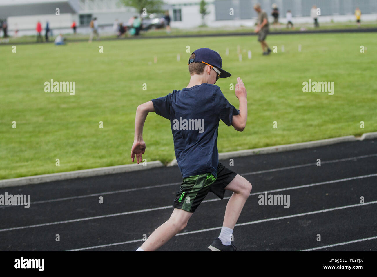 Young boy competing in track & field's, distance race, wearing shorts, t-shirt, hat and sunglasses.. Model released Stock Photo