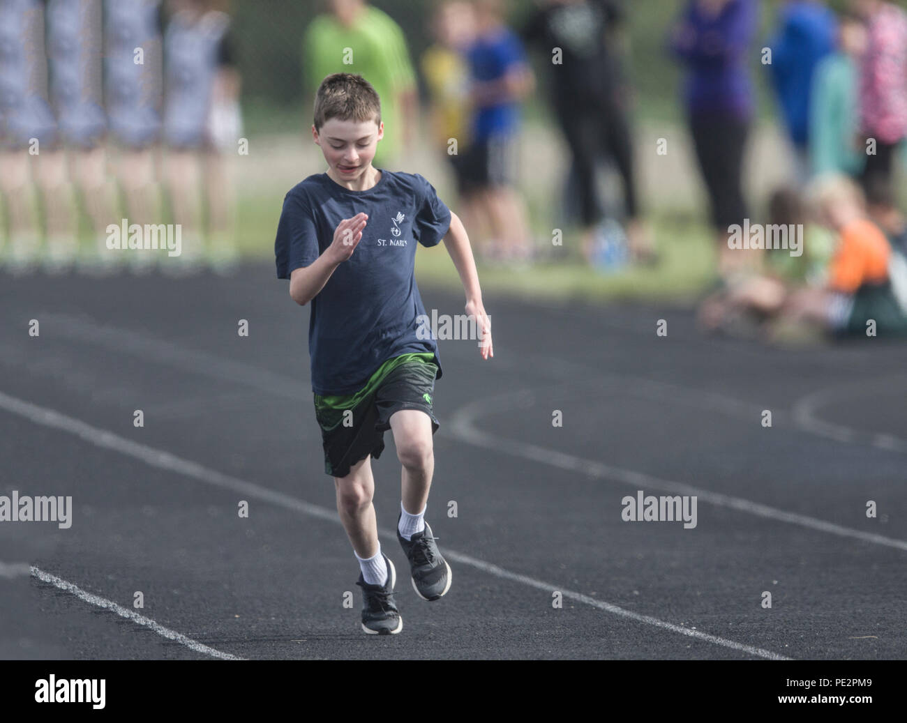 Young boy competing in track & field's, distance race, wearing shorts, t-shirt,. Model released Stock Photo