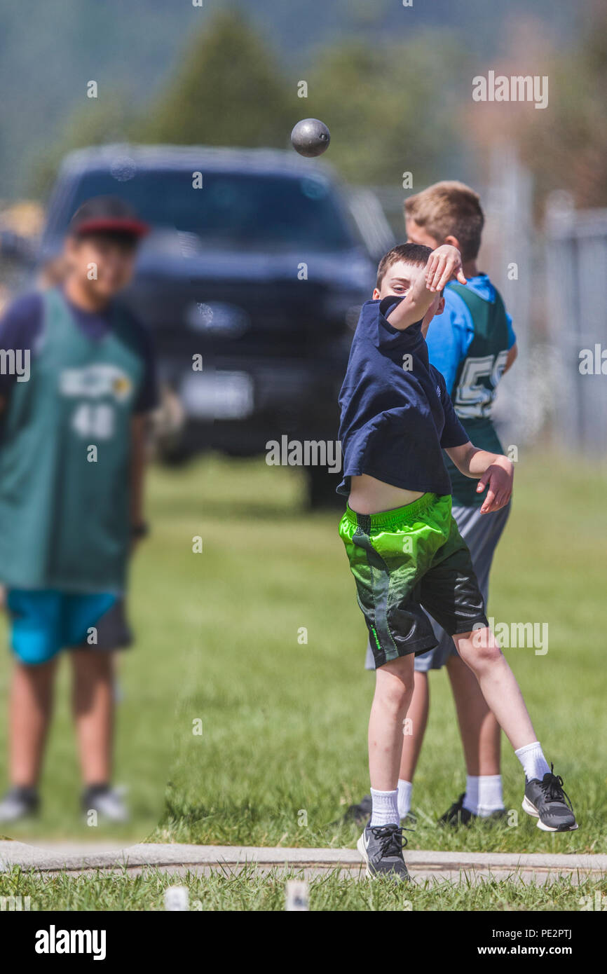 Young boy competing in track & field's shot put. Wearing t-shirt and shorts, just releaed shot put. Model released. Stock Photo