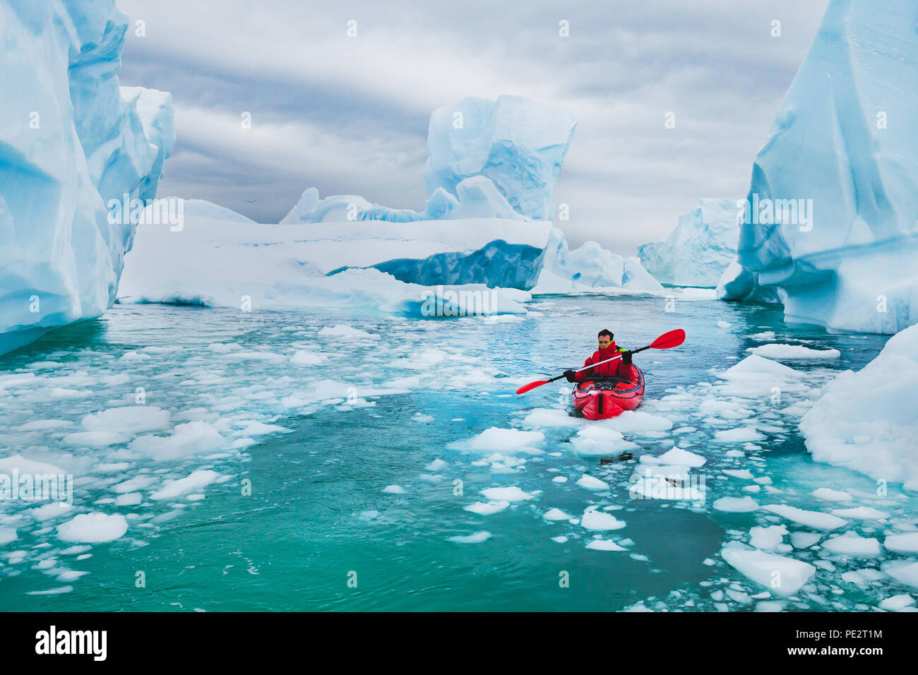 extreme tourism, winter kayaking in Antarctica, adventurous man paddling on sea kayak between icebergs Stock Photo