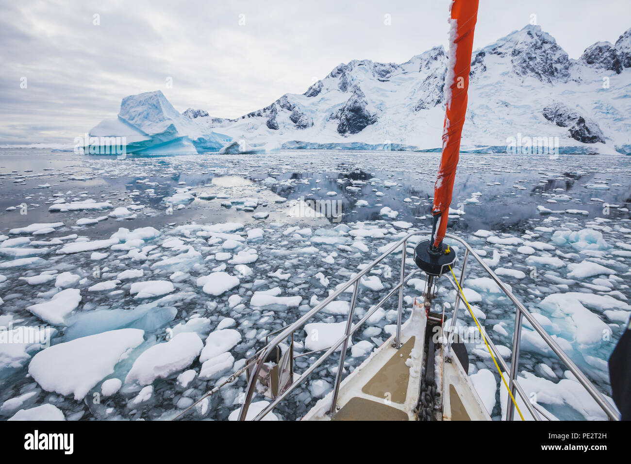 sailing boat in Antarctica, yacht navigation through icebergs and sea ice Stock Photo