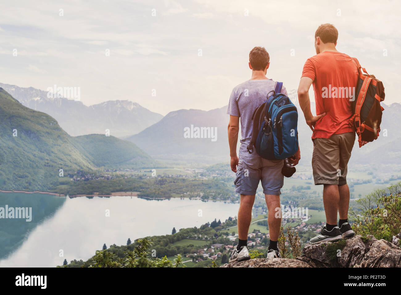 friends hiking in Europe, hike in Alps in Annecy, France, outdoor summer activity with backpack, two people backpackers standing on top of mountain an Stock Photo