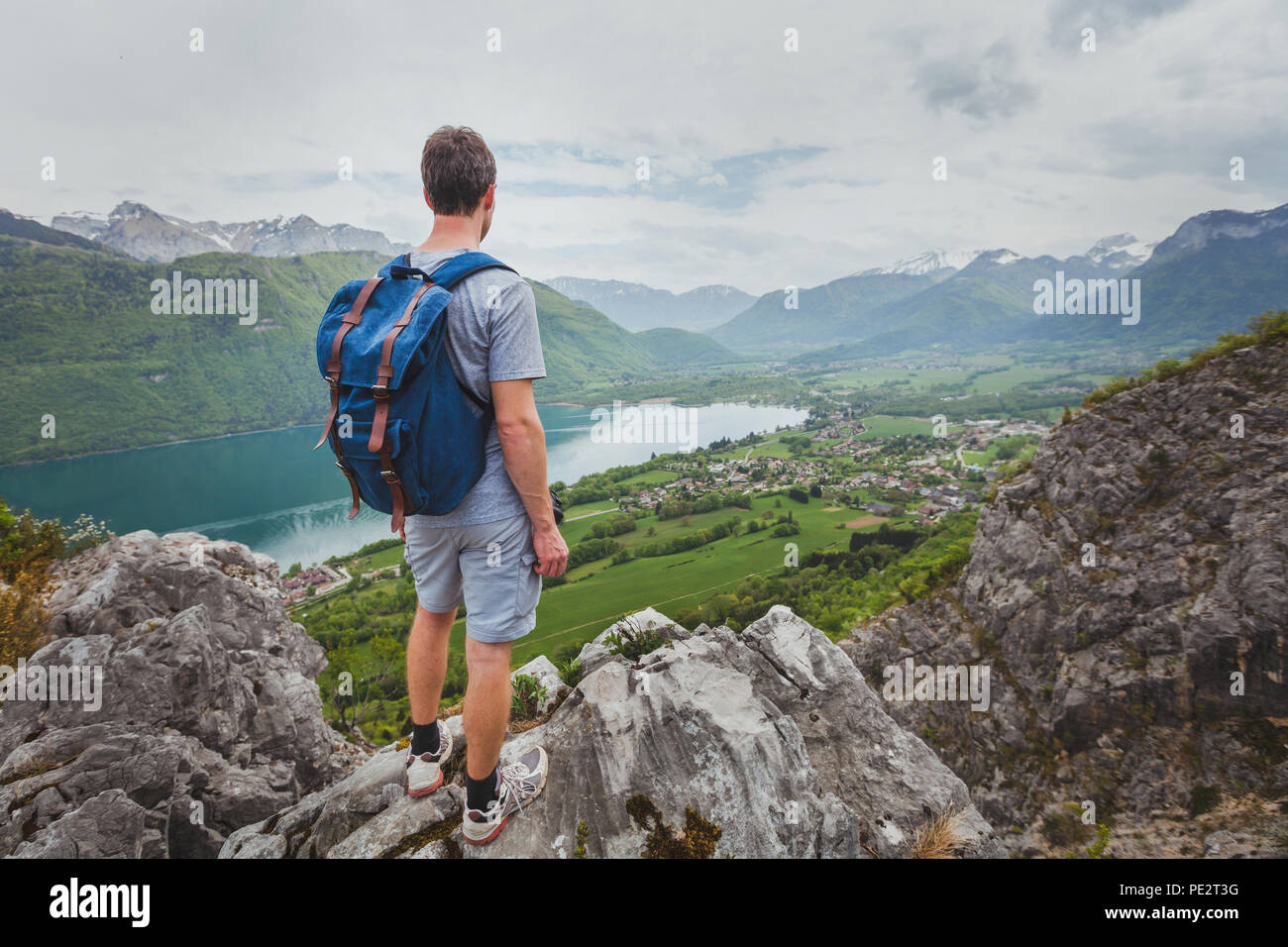 hiking in mountains, achievement concept, summer outdoors leisure activity, hiker with backpack enjoying the view of valley and lake Stock Photo