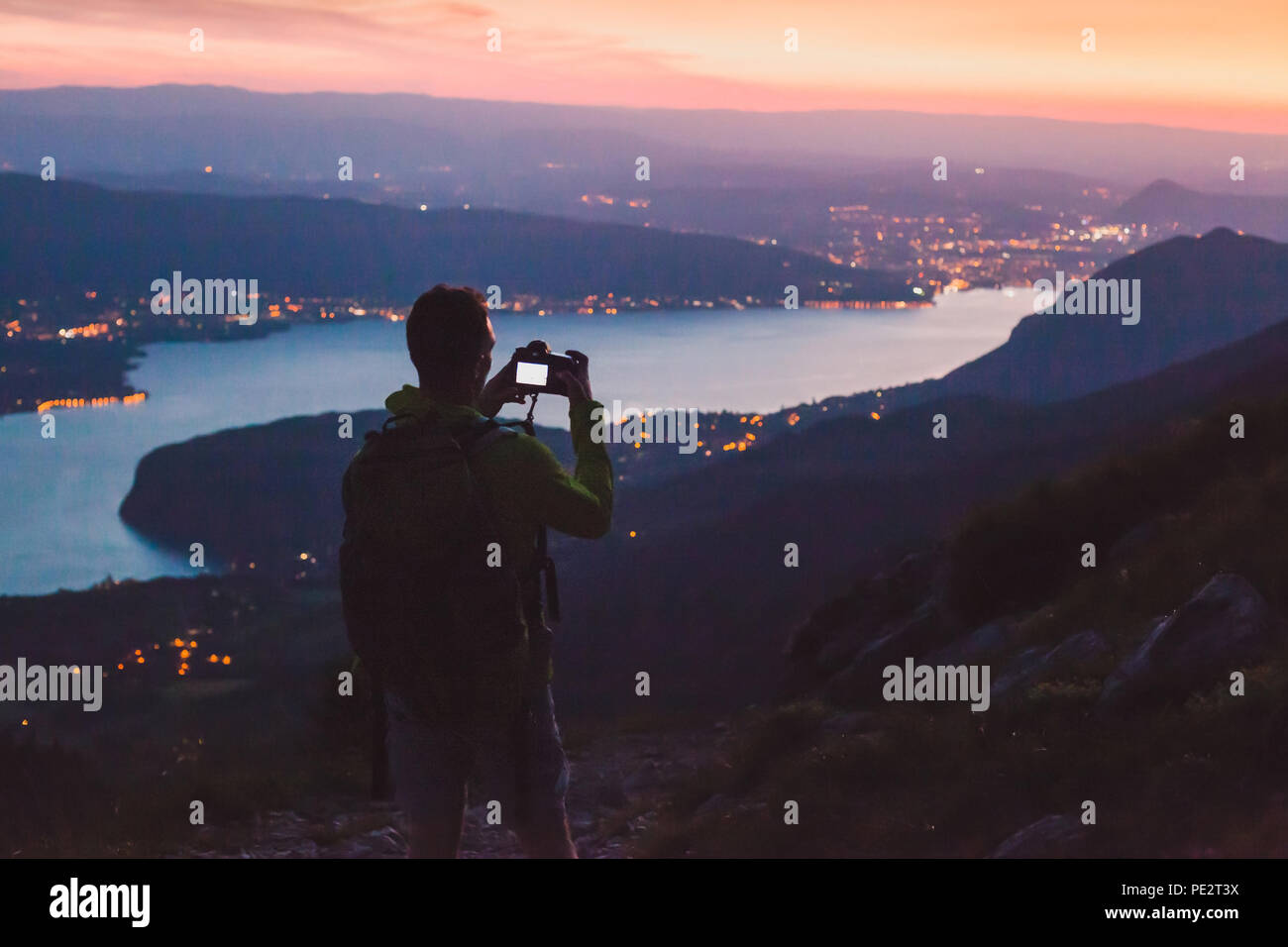 photographer taking photo on dslr camera at night after sunset twilights, city panoramic mountain landscape low light, dusk Stock Photo