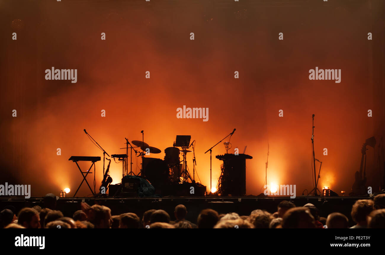 empty concert stage on music festival, instruments silhouettes, microphones drums guitars and crowd of people Stock Photo