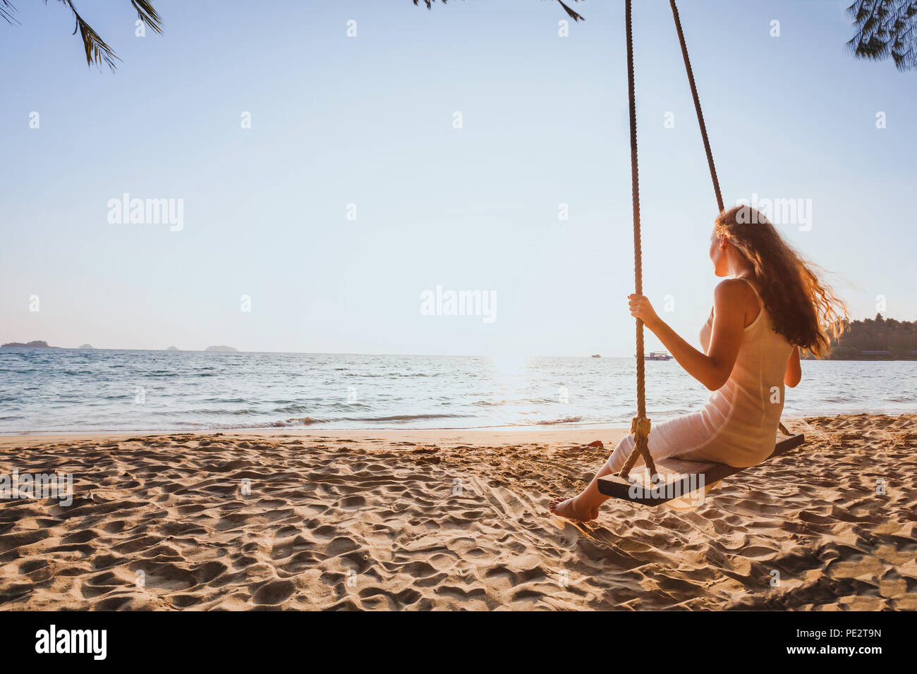dream and happiness concept, romantic beautiful carefree woman relaxing on the swing at sunset beach, summer holidays, vacation travel and relaxation, Stock Photo