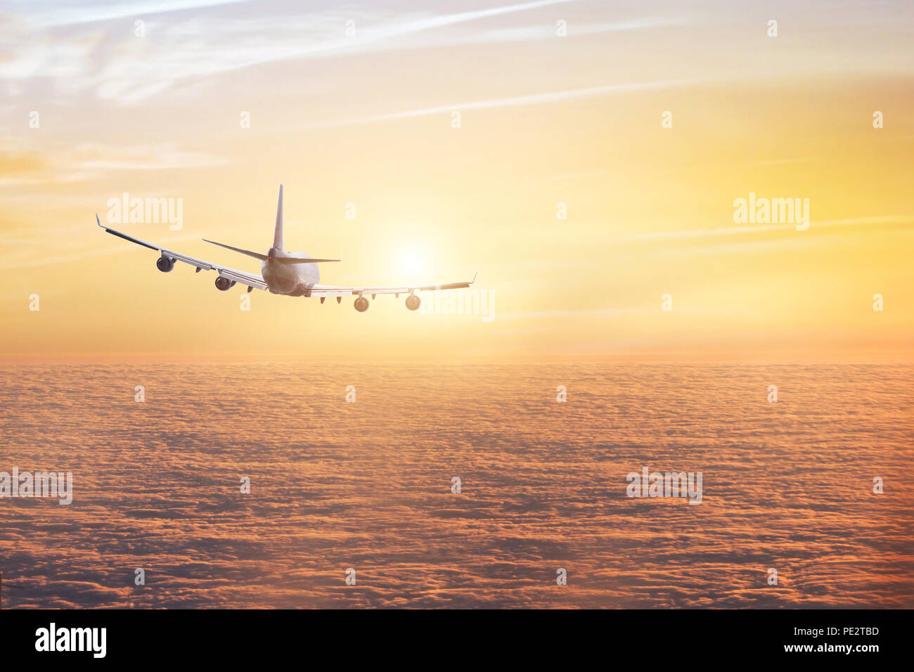 airplane flying above clouds, aircraft traveling in the sky, flight at sunset Stock Photo