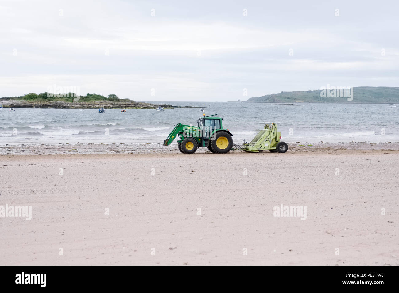 Tractor on sandy beach cleaning up rubbish and litter to help clean the environment and prevent pollution Stock Photo