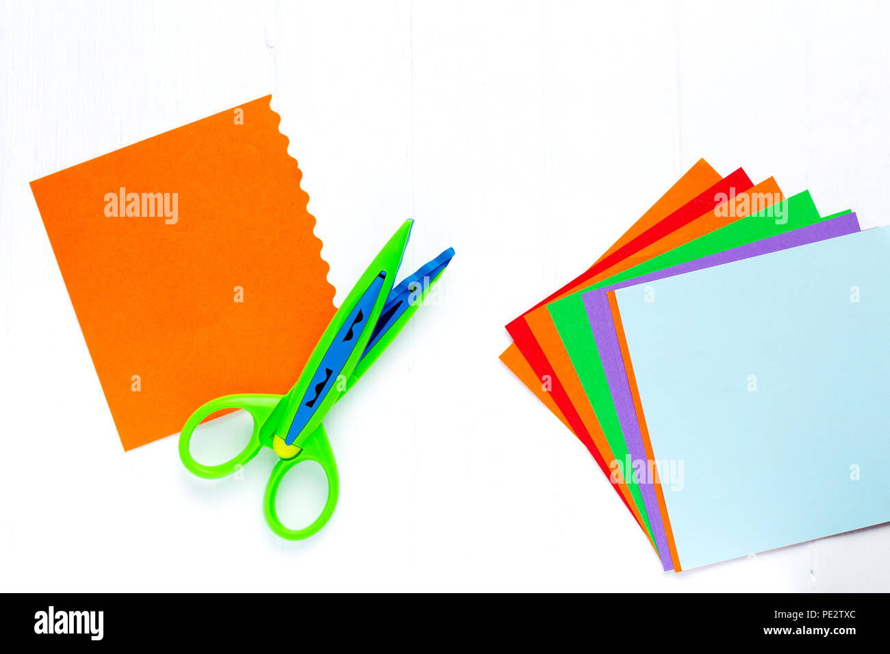 Color paper for origami is a fan, scissors with a wavy edge. On white