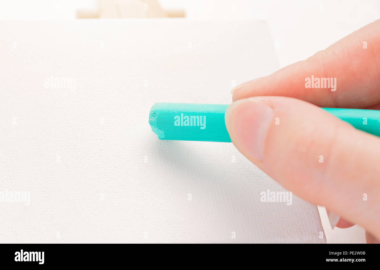 A female hand holds a chalk, a pastel of a hollow color. Stock Photo