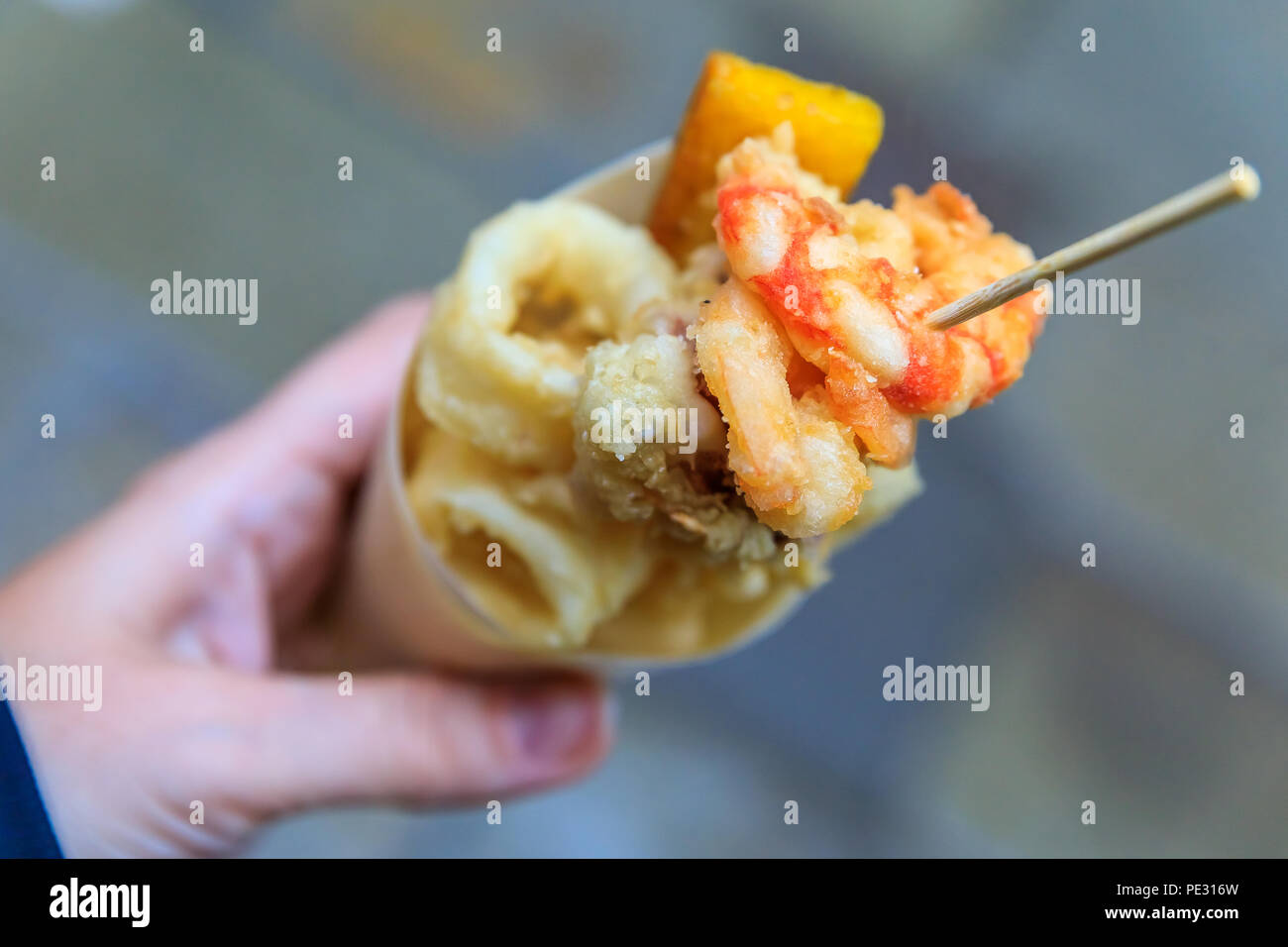 Italian street food in Venice - fritto misto (mix of fried fish, calamari, or squid, and shrimp) in a cone on the go Stock Photo