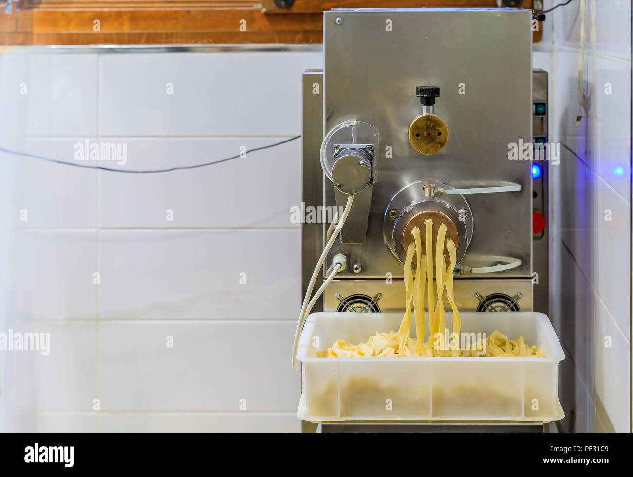 Industrial pasta maker pushing out fresh pasta at an Italian restaurant Stock Photo