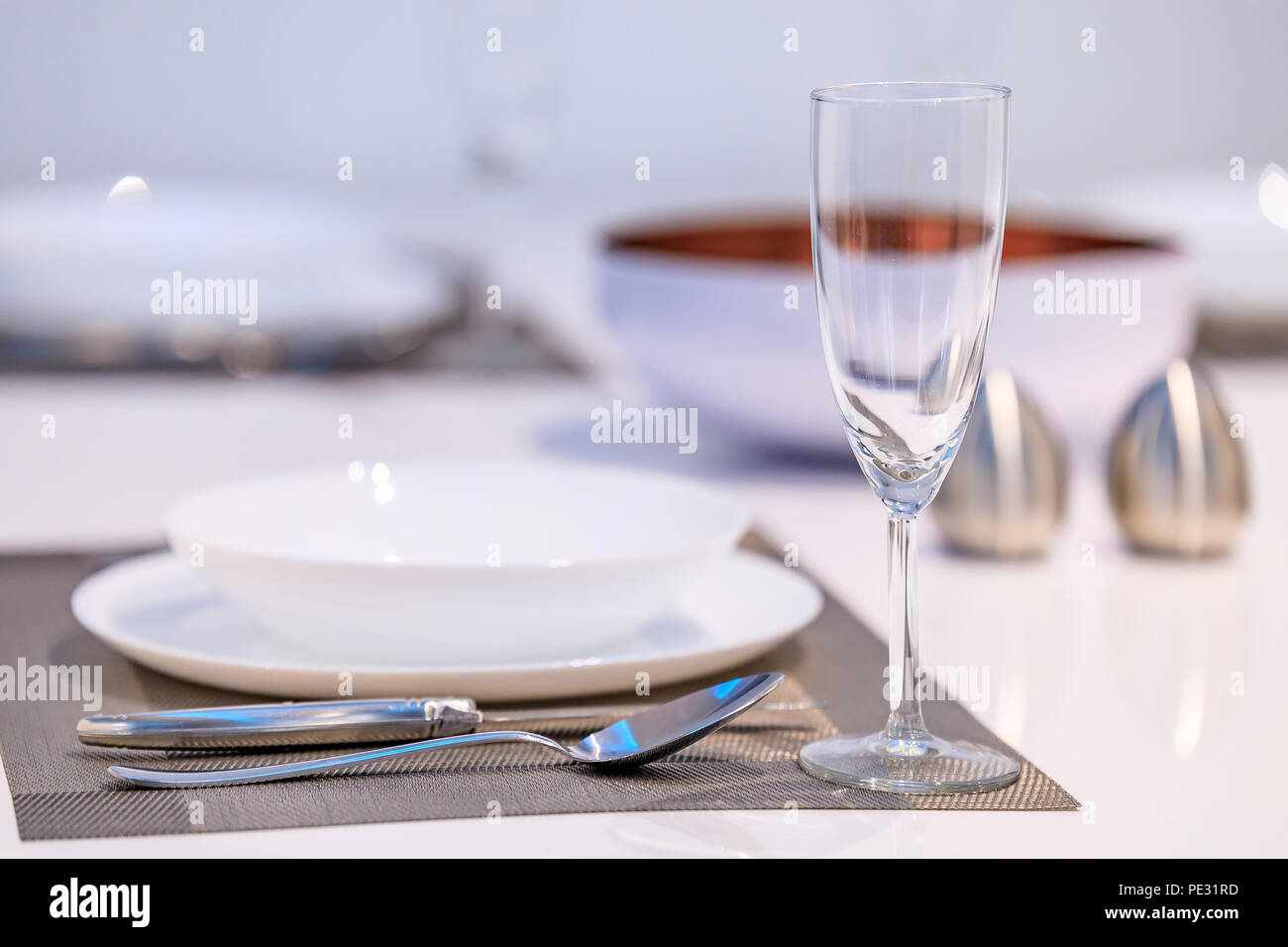 Table setting in a modern dining room with a white table and flatware